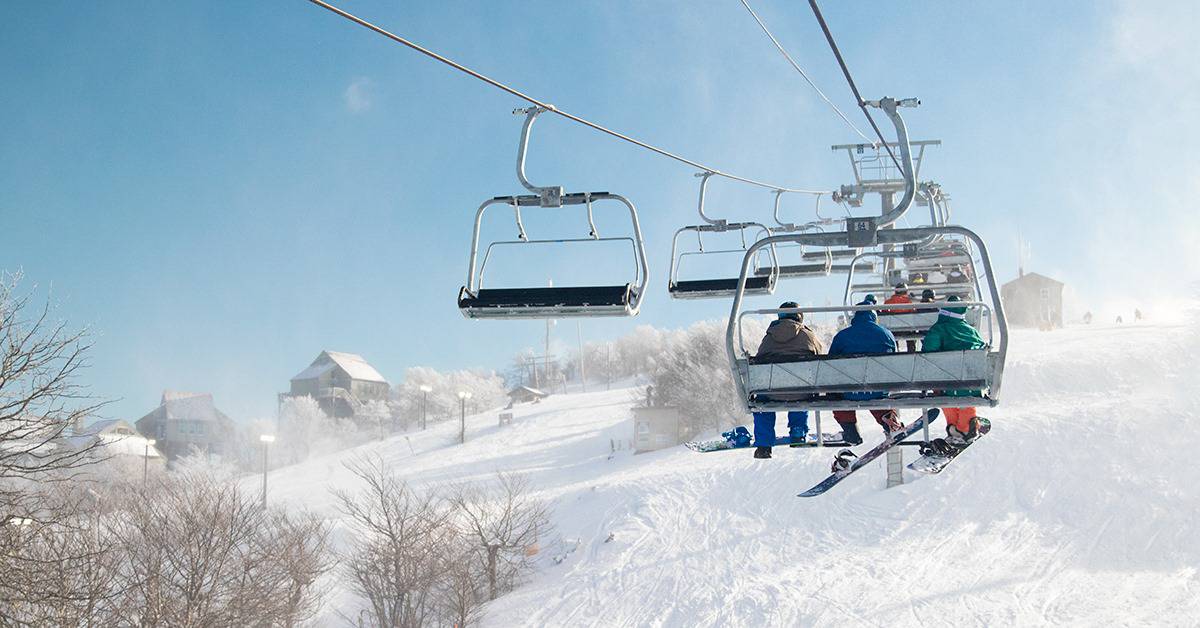 People riding the ski lift up to the top of the mountain.