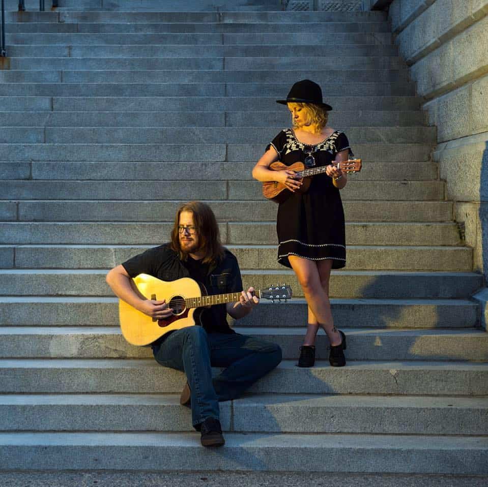 Male and Female holding musical instruments standing on the steps.