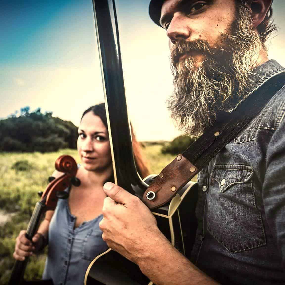 Man and woman stand next to each other holding their instruments.