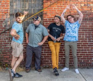 Donnie & the Dry Heavers stand against a brink wall posing in a line.