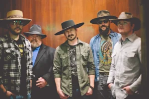 five men standing in a room with hats on